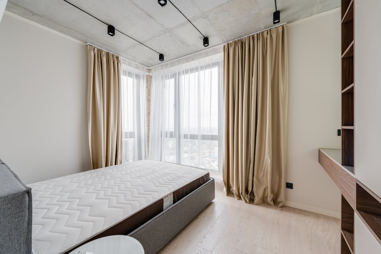 Spacious modern bedroom with cozy bedding and natural light.